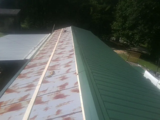 Old rusted panels beside newly installed green metal roofing — Wind Damage Roof Repair by Roofing Brothers in Missouri City