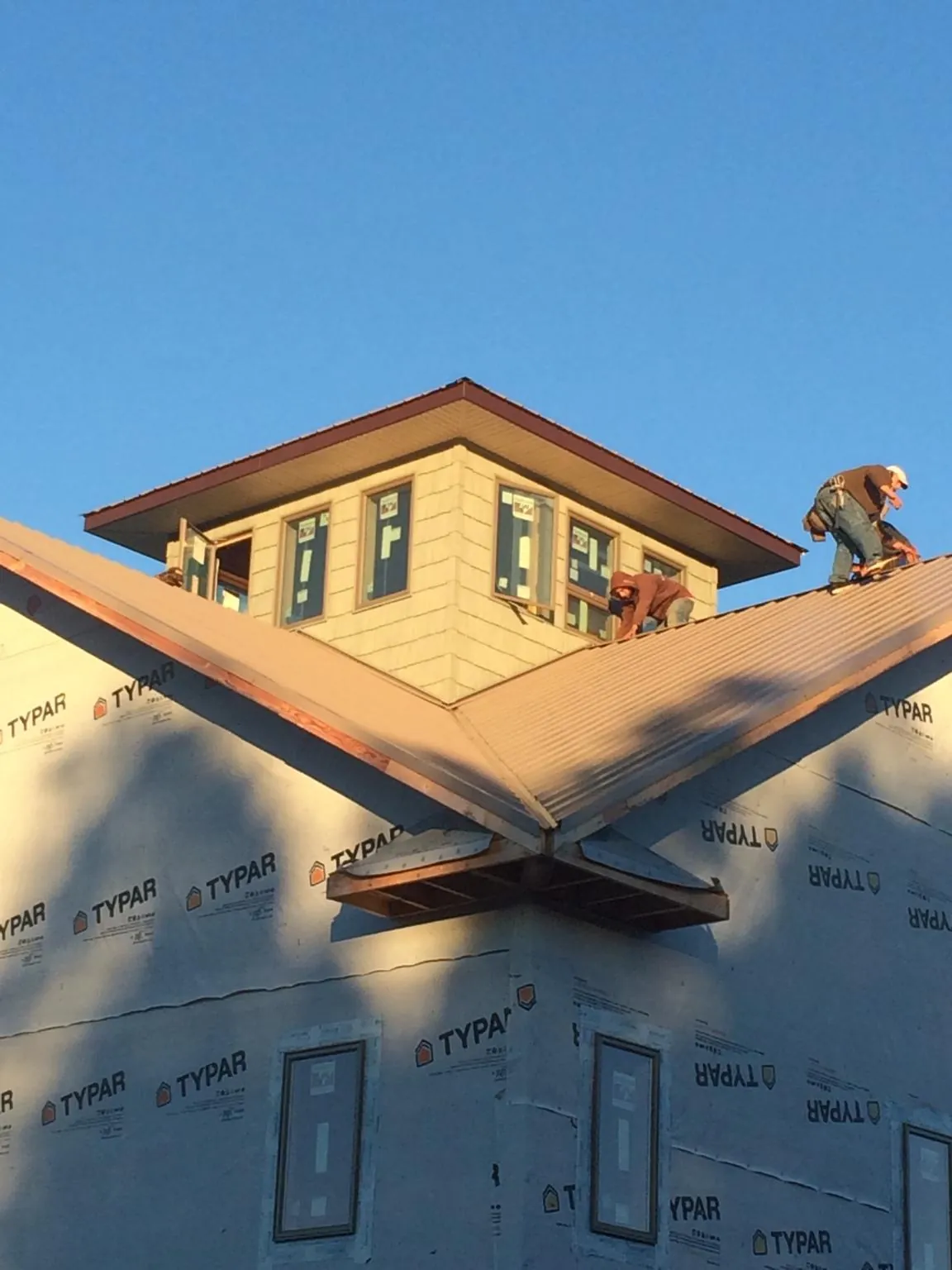 Roofers working around a rooftop cupola on a new metal roof at sunset — Roof Waterproofing in Missouri City by Roofing Brothers